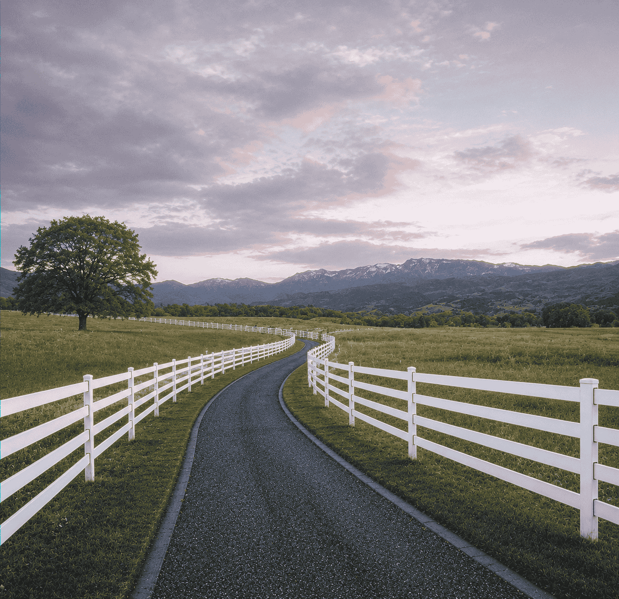 Aerial view of a Utah horse property showing elegant curved white Kuptz Steel Fence lines with a mountain backdrop